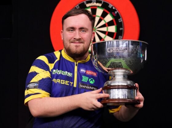 Luke Littler levanta o troféu do Grand Slam de Dardos.