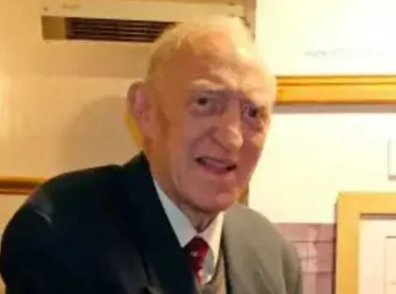 Uma colagem de imagens contendo 1 imagens, a imagem 1 mostra um homem de paletó e gravata olhando para a câmera, com documentos emoldurados atrás dele